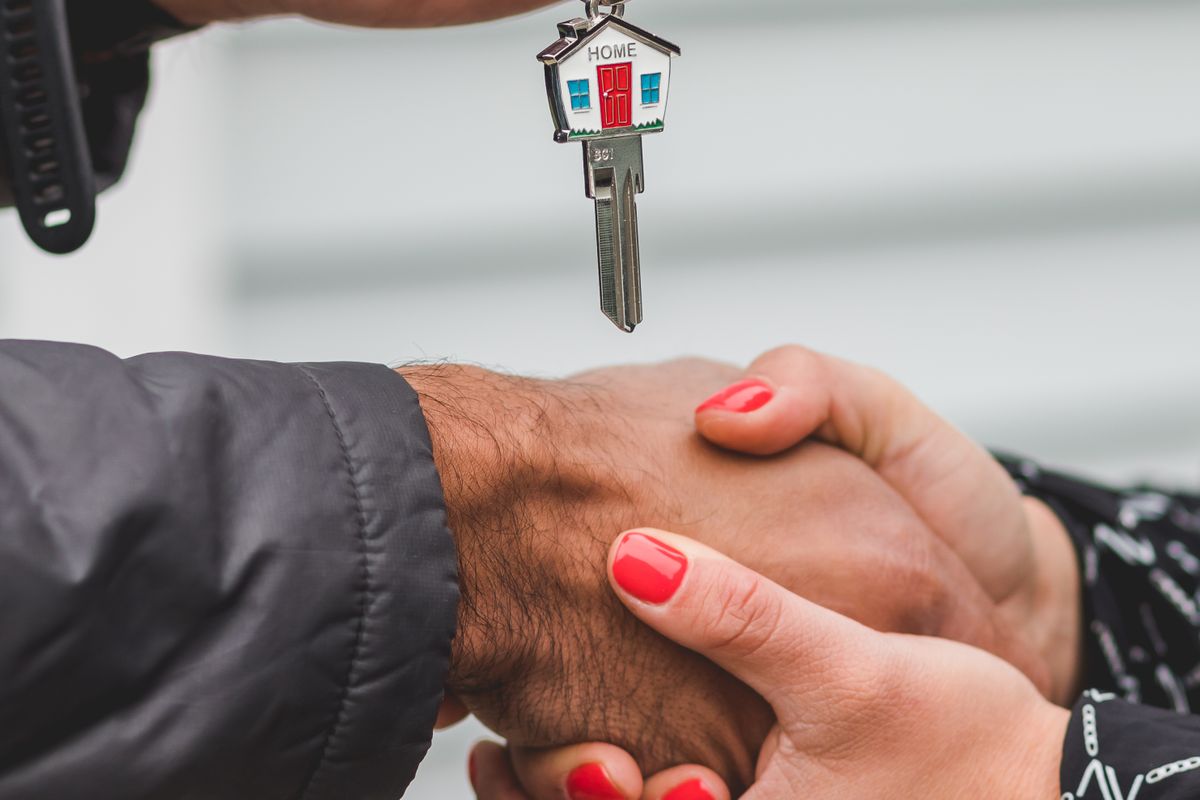Two people shaking hands as a house key is handed over