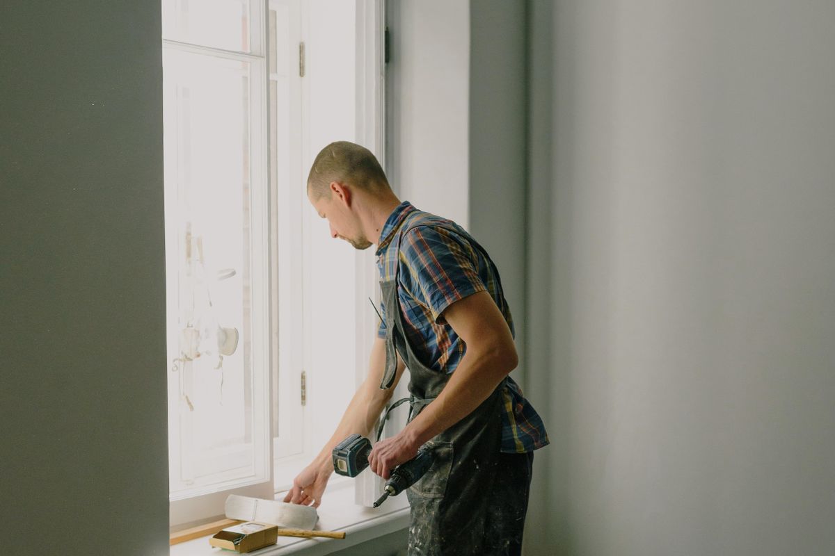 A technician carrying out repair work beside an apartment window